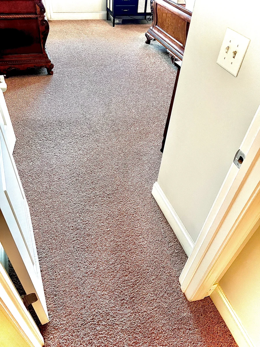 Bedroom carpet with visible discoloration near the doorway before cleaning